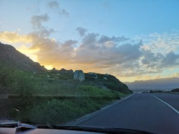 Road against sky seen through car windshield during sunset