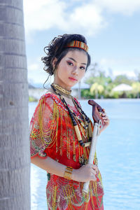 Portrait of young woman standing against lake