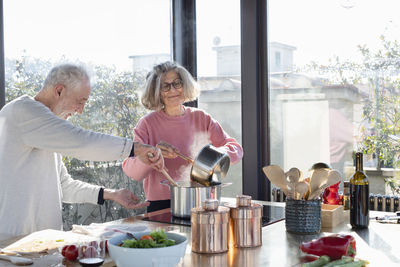 Senior couple cooking together while standing in kitchen at home