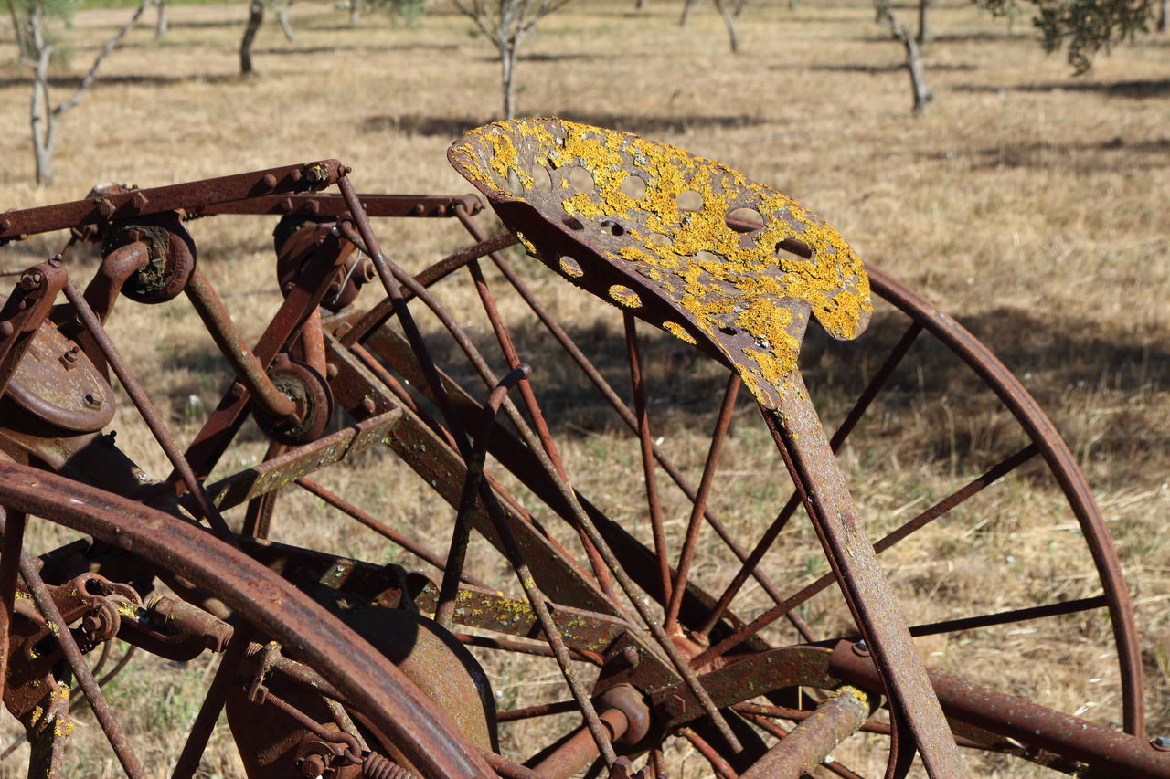 CLOSE-UP OF ABANDONED RUSTY METAL ON FIELD