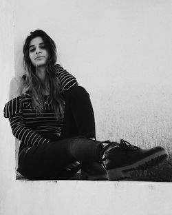 Portrait of woman sitting on retaining wall