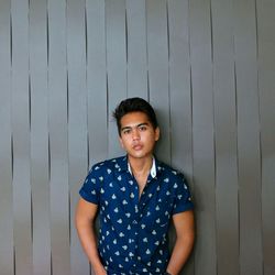 Portrait of confident young man standing against wall