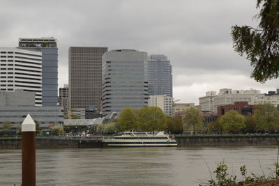 Modern buildings by river against sky in city