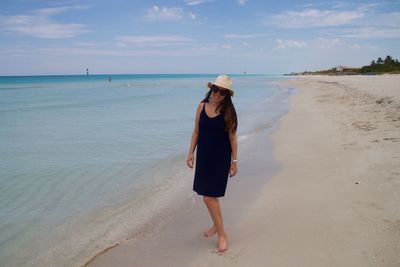 Full length of young woman standing on shore at beach