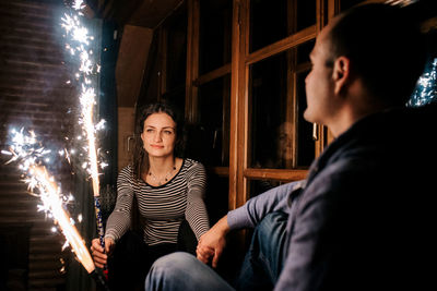 Young man sitting in illuminated room