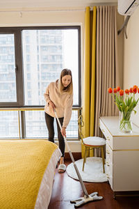 Portrait of young woman standing by window at home