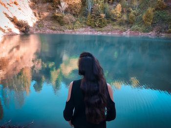 Rear view of woman standing by lake