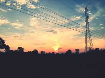 Silhouette of electricity pylon at sunset