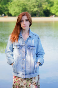 Portrait of young woman standing against lake