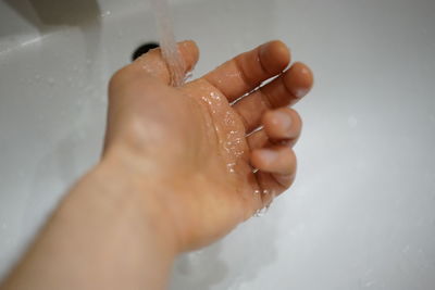 Cropped image of hand touching water at home