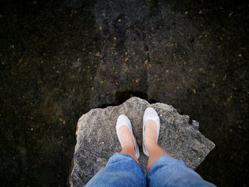 Low section of woman standing on rock in lake