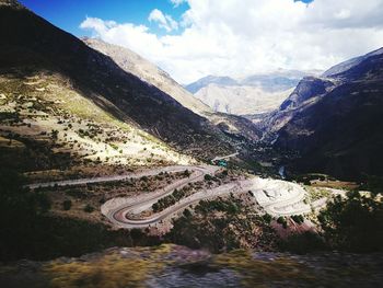 Winding road and rocky mountains against cloudy sky