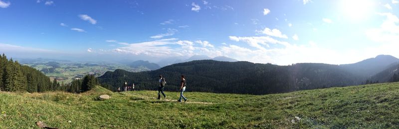 Panoramic view of hikers walking on field