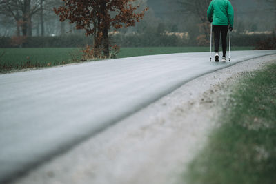 Low section of man walking on road during foggy weather