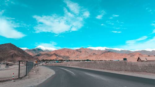 Road by mountains against blue sky