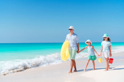 Father and daughters walking on beach