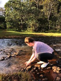 Side view of young woman standing by lake