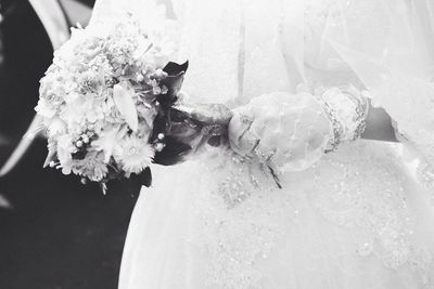 Mid section of a bride holding bouquet