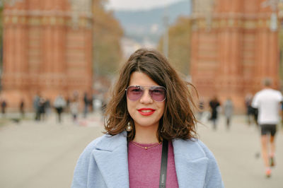 Portrait of young woman standing against arc de triomf