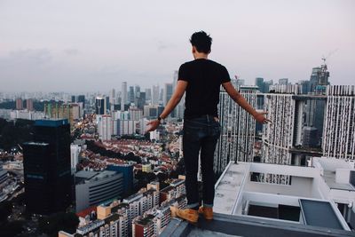 Rear view of man standing on terrace against cityscape