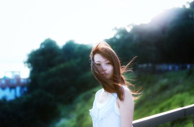 Thoughtful mid adult woman with tousled hair looking away in park