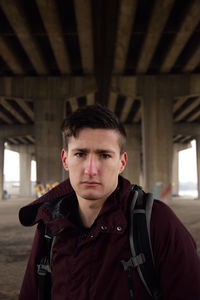 Portrait of young man standing against ceiling