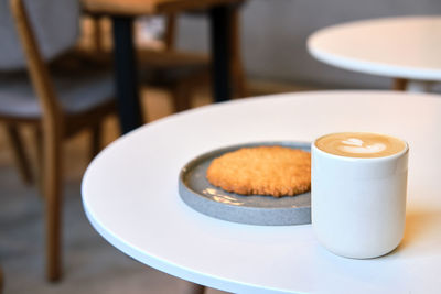 Morning brunch in cafe is on table. giant cookie and cappuccino with beautiful milk foam