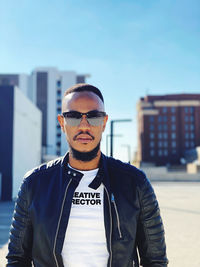 Portrait of young man wearing sunglasses standing against sky