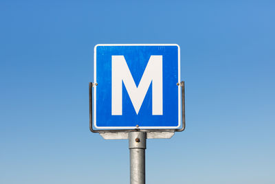 Low angle view of road sign against clear blue sky