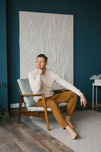 Handsome young man sitting in armchair indoors person