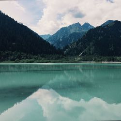 Scenic view of lake by mountains against sky