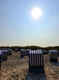 Hooded chairs on beach against sky