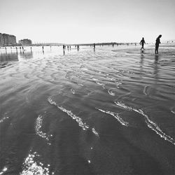 People standing on beach against clear sky