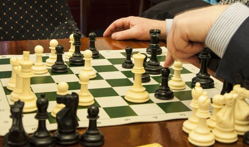 Cropped image of person playing chess on table