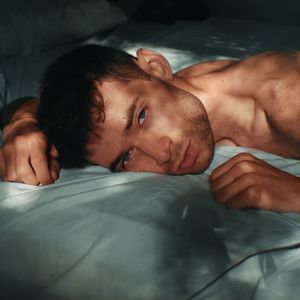 Portrait of shirtless man lying in bed