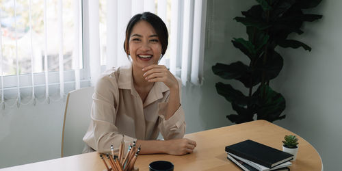 Young woman using phone while sitting on table