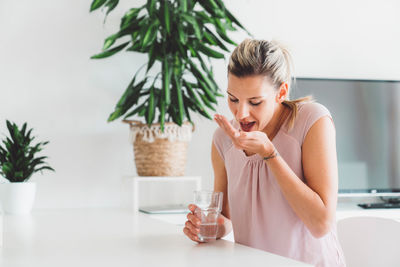 Young woman drinking water while sitting at home