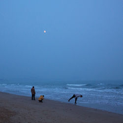 People on beach against clear sky