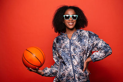 Portrait of smiling young woman against red background