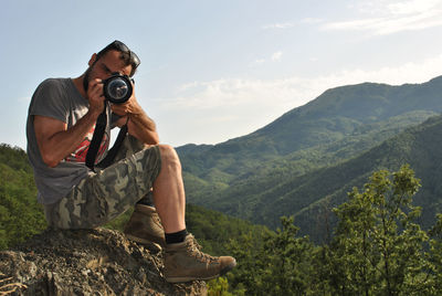 Man photographing on mountain against sky