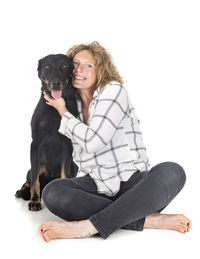 Mid adult woman with dog sitting against white background
