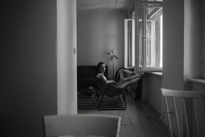 Rear view of woman sitting on chair at home