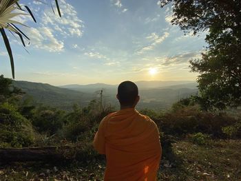 Rear view of monk looking at mountain against sky