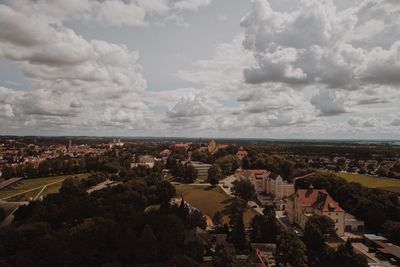 Aerial view of cityscape against cloudy sky