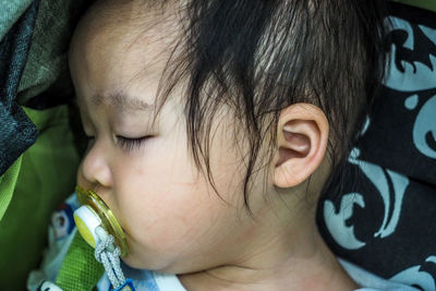 Close-up of cute girl with pacifier sleeping on bed