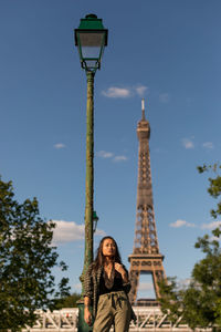 Low angle view of woman standing against eiffel tower