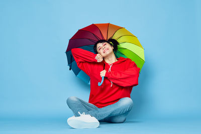 Woman with red umbrella against blue background