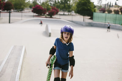 Girl carrying skateboard while walking at park