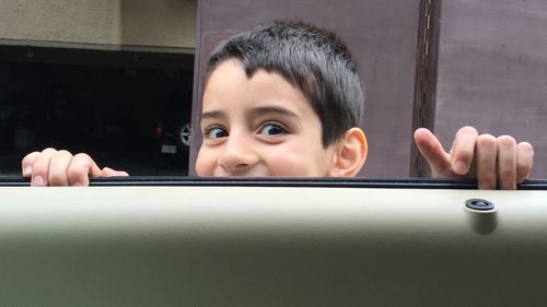 Portrait of smiling boy holding car door