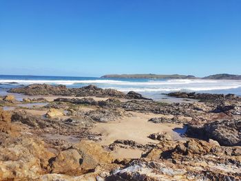 Scenic view of beach against clear blue sky